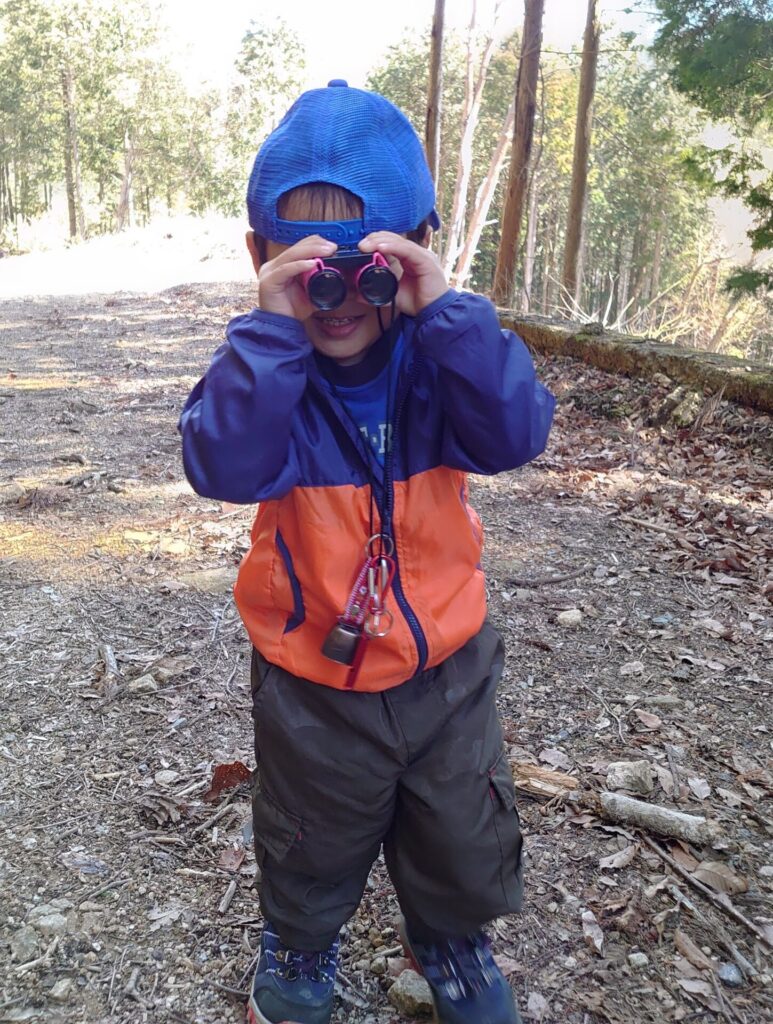 子供が双眼鏡で山の景色を楽しむシーン。子連れ登山のモチベーション系アイテムの実例