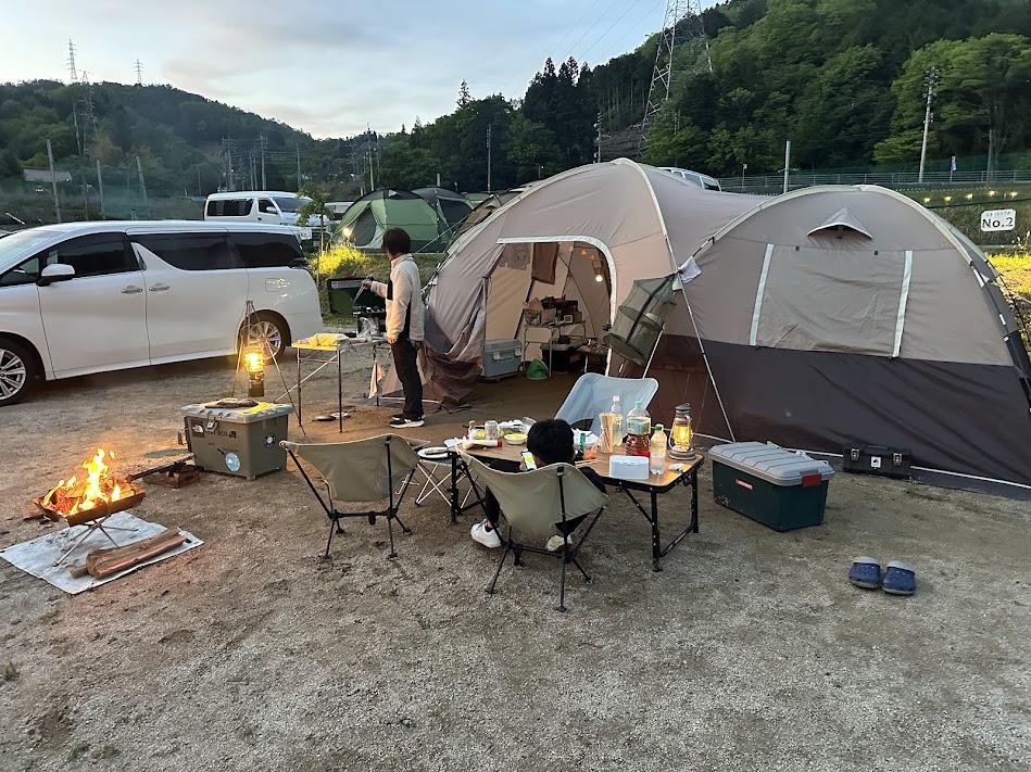 夕方のキャンプサイト全景(焚き火・テント・ランタン)