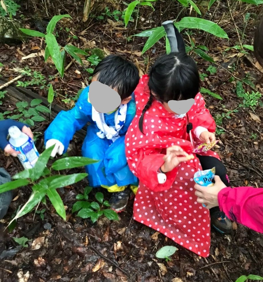 レインコートを着た保育園時代の子どもが雨に濡れて寒そうにしている様子