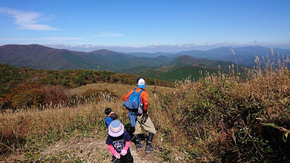 深入山の草原の稜線から広島の山々を望む親子