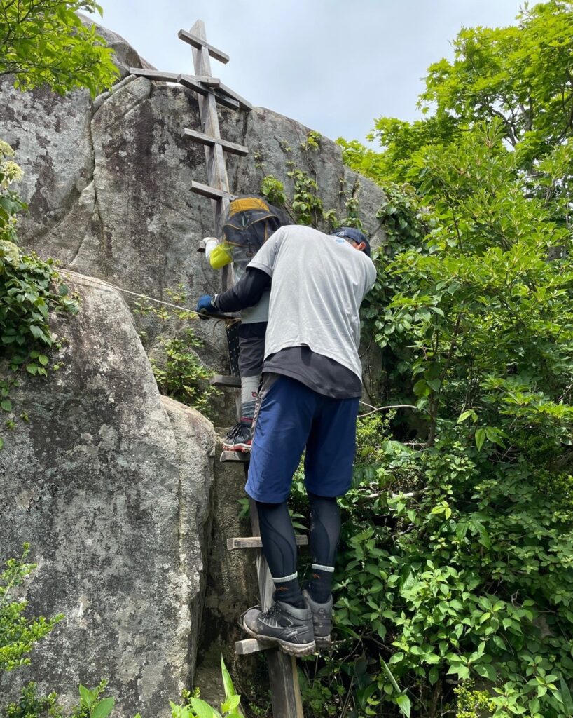 旧羅漢山の大岩に掛かるはしごを登る親子
