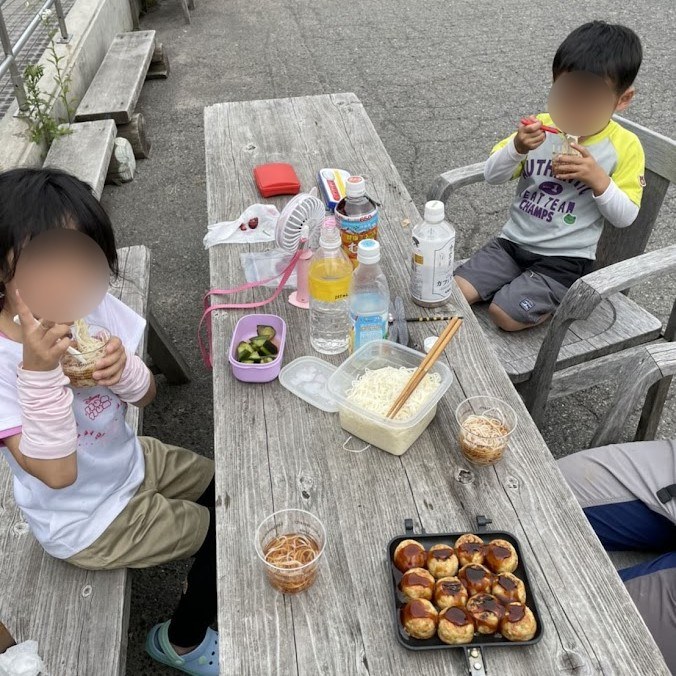 下山後、センターハウス前のテーブルでたこ焼きを食べる子どもたち