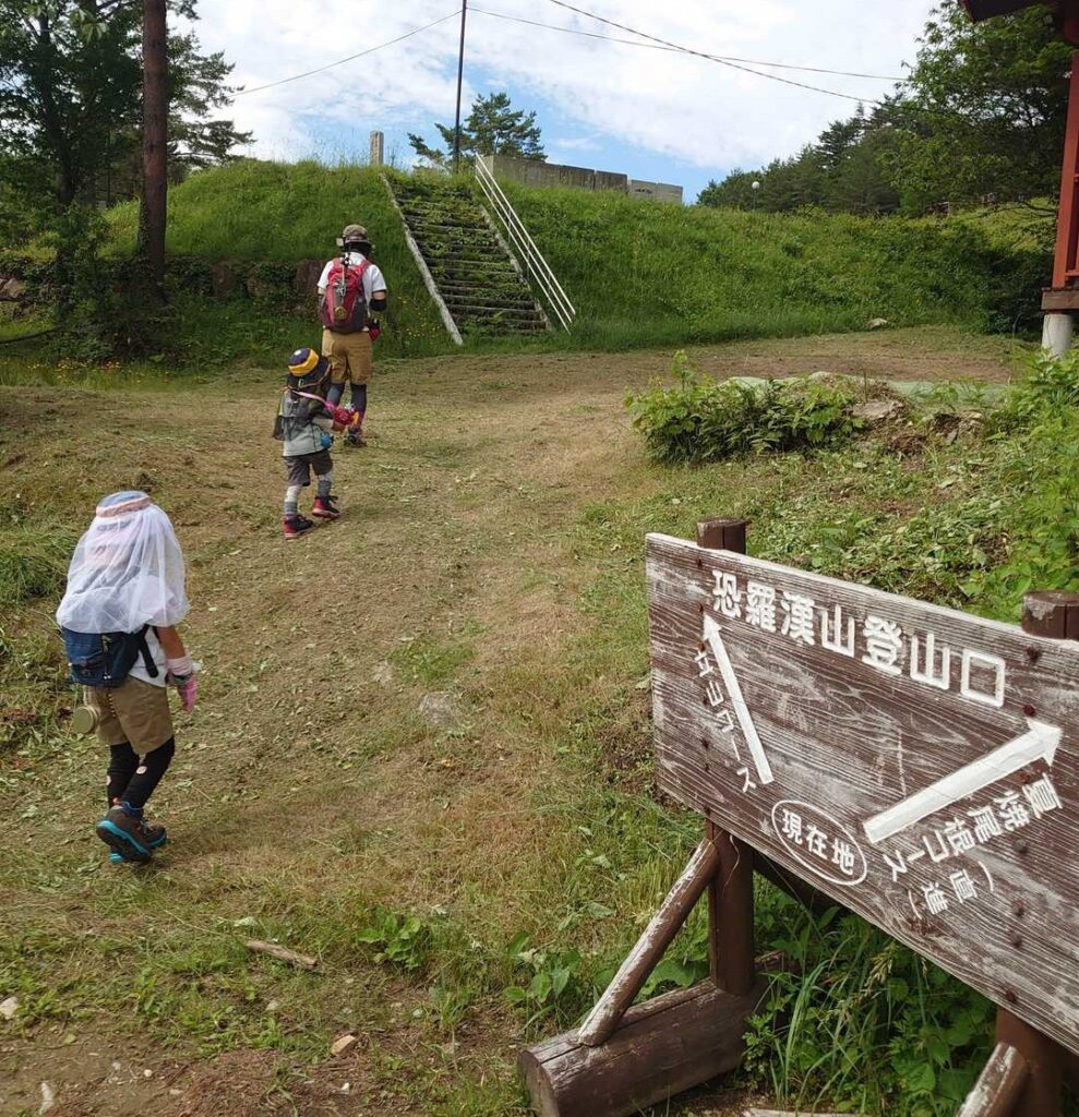 「恐羅漢山登山口」の道標の脇を通って登山口へ向かう家族