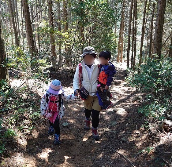 3歳の息子を抱っこし、6歳の娘と手をつないで登山道を登る様子