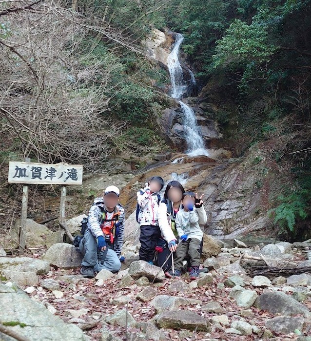 南原峡の登山口近くにある加賀津ノ滝の前に立つ家族4人