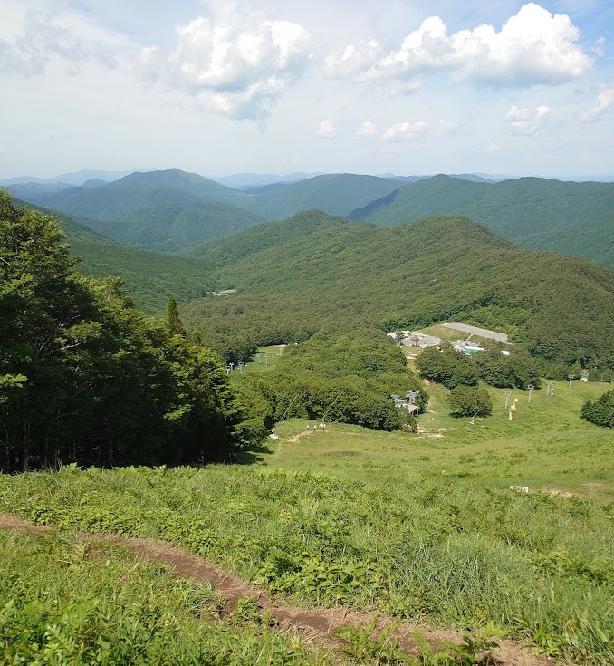 恐羅漢山の山頂近くから見下ろす、ゲレンデとキャンプ場、遠くに連なる山並み