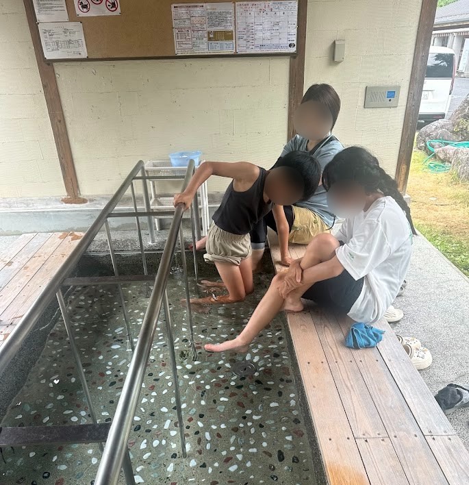 湯来リバーサイドキャンプ場の無料の足湯に足をつける子どもたち