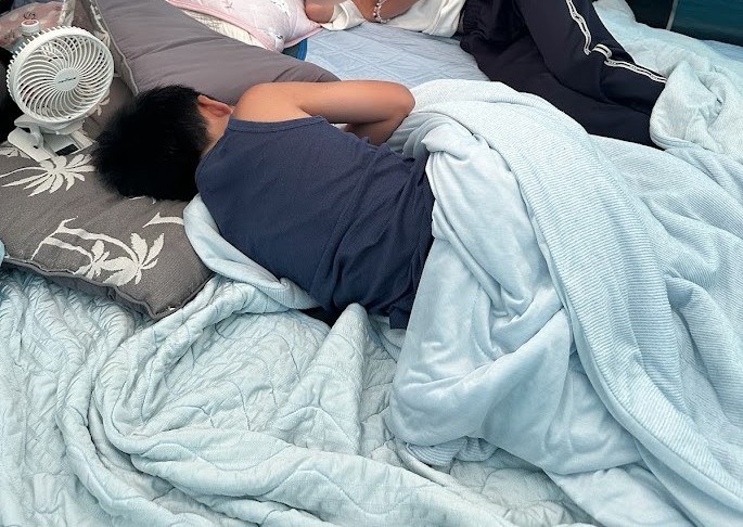 テント内で卓上扇風機を回しながら眠る子ども