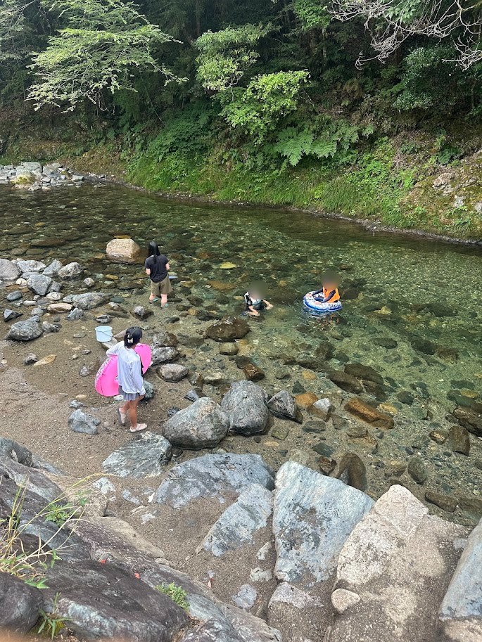 浮き輪と網を持って水内川に入る子どもたち