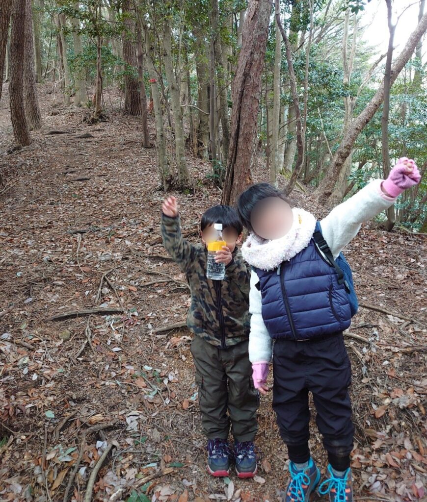 湯たんぽ代わりの温かいボトルを持ち、両手を上げて笑う6歳の娘と4歳の息子