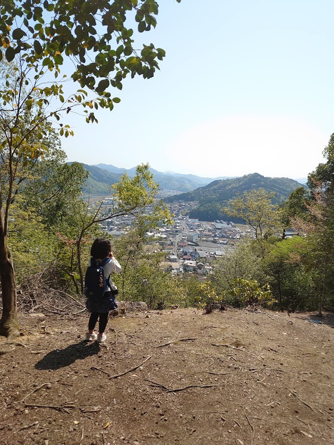 下山中の山道から吉田の町並みを見下ろす娘の後ろ姿