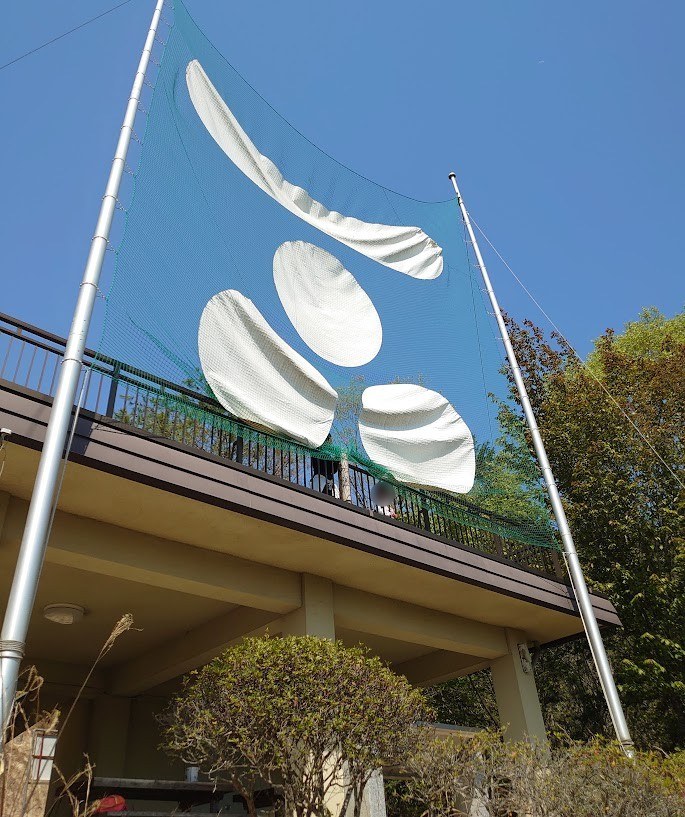 郡山公園の展望台の建物と、ネットに取り付けられた毛利家の家紋の飾り