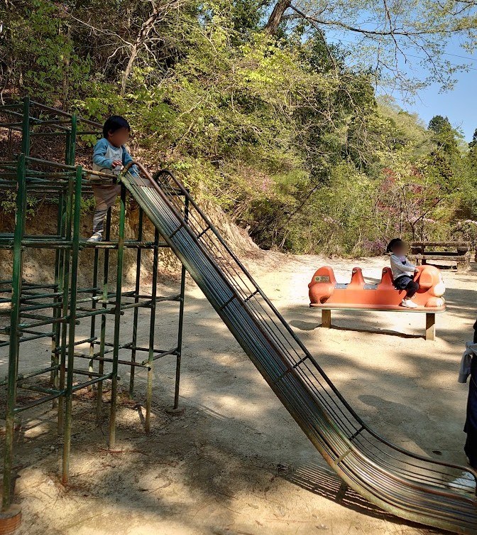 郡山公園の急なすべり台を登る息子と、奥のレトロな乗り物に座る娘