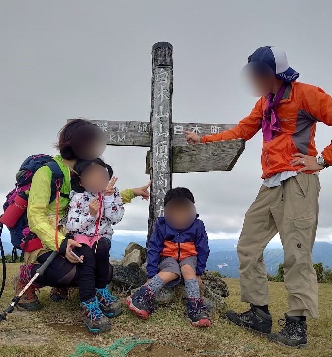 白木山の山頂標識の前で家族4人の記念写真