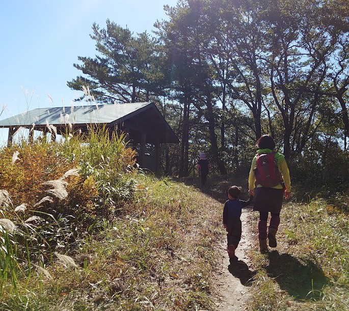 深入山の東屋のそばの登山道を、手をつないで歩く母と息子