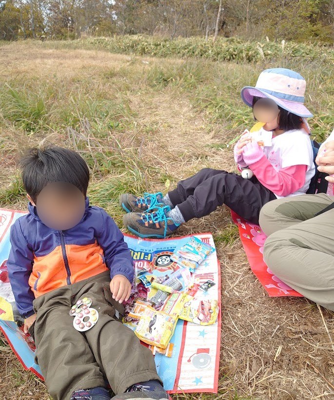 雲月山の山頂でレジャーシートを広げておやつを食べる子どもたち