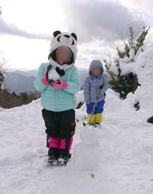 牛頭山の山頂の雪の上に立つ娘と息子