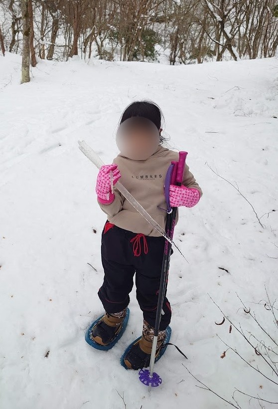 ピンクの手袋をつけて、つららを持つスノーシューの子ども