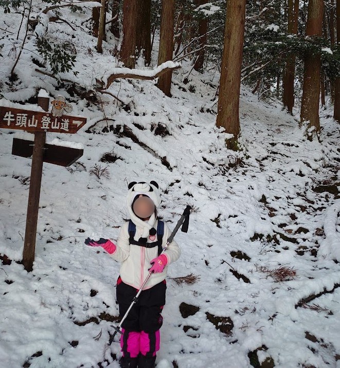 雪の中の牛頭山登山道の標識と娘