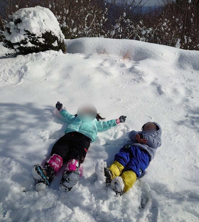雪の上で寝転ぶ子ども2人