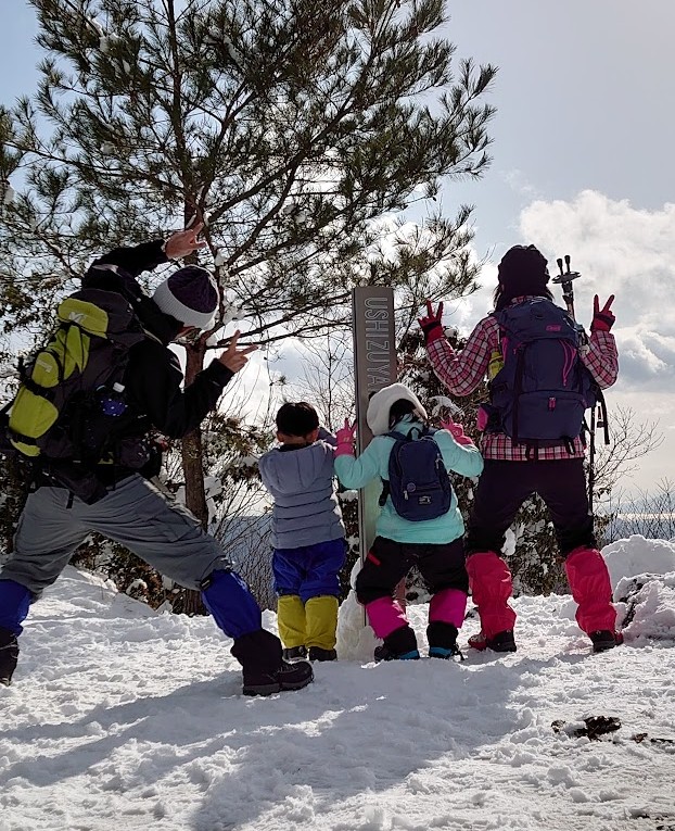 牛頭山の山頂で記念撮影をする家族4人