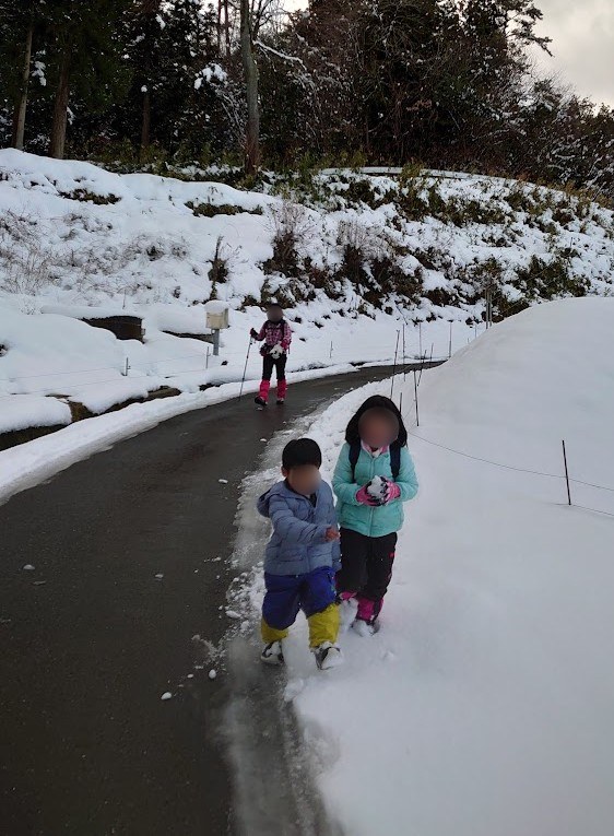 下山後に雪の残る車道を歩く息子と娘
