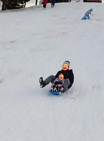 道の駅どんぐり村の雪の坂をソリで滑る親子