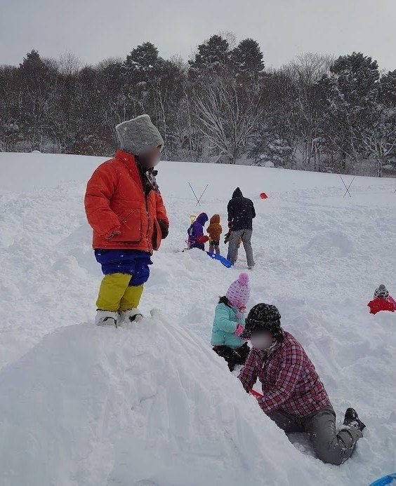 雪の上でそり遊びをする子どもたち
